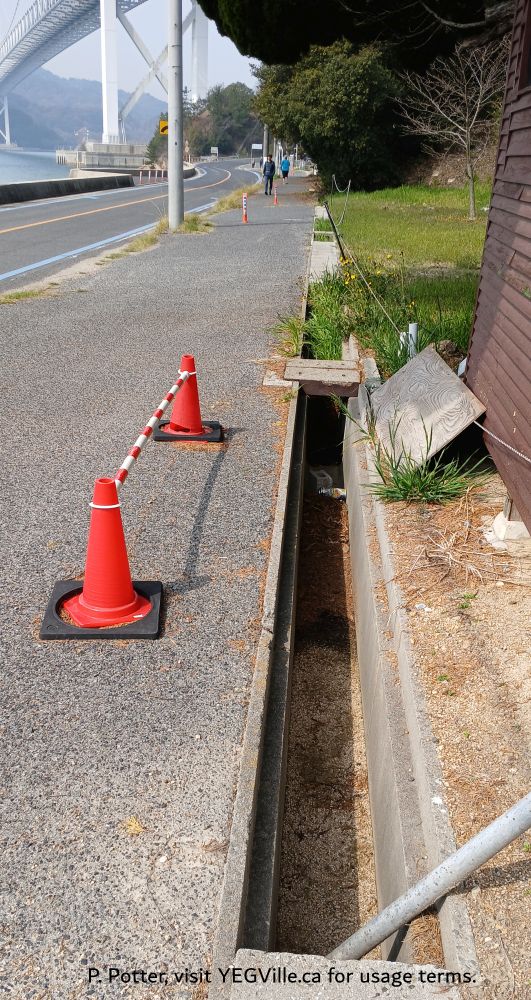 Open gutters to direct rain water are a definite hazard while cycling the route, 2026-03-30, P. Potter.