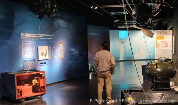 A visitor reading about mine-sweeping operations, Kure and Japan Defense Museum, 2026-04-12, P. Potter.